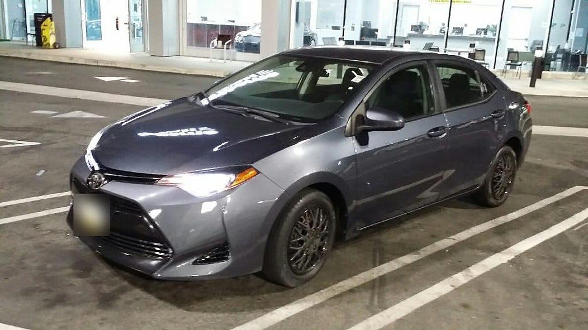 Gray sedan parked in a lit parking lot at night.